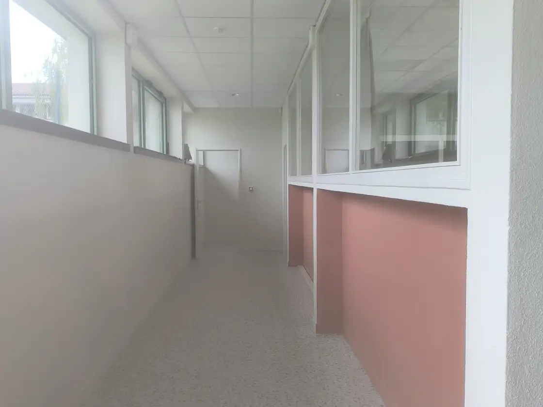Couloir de bureaux avec cloisons vitrées et sol nettoyé, en entretien régulier