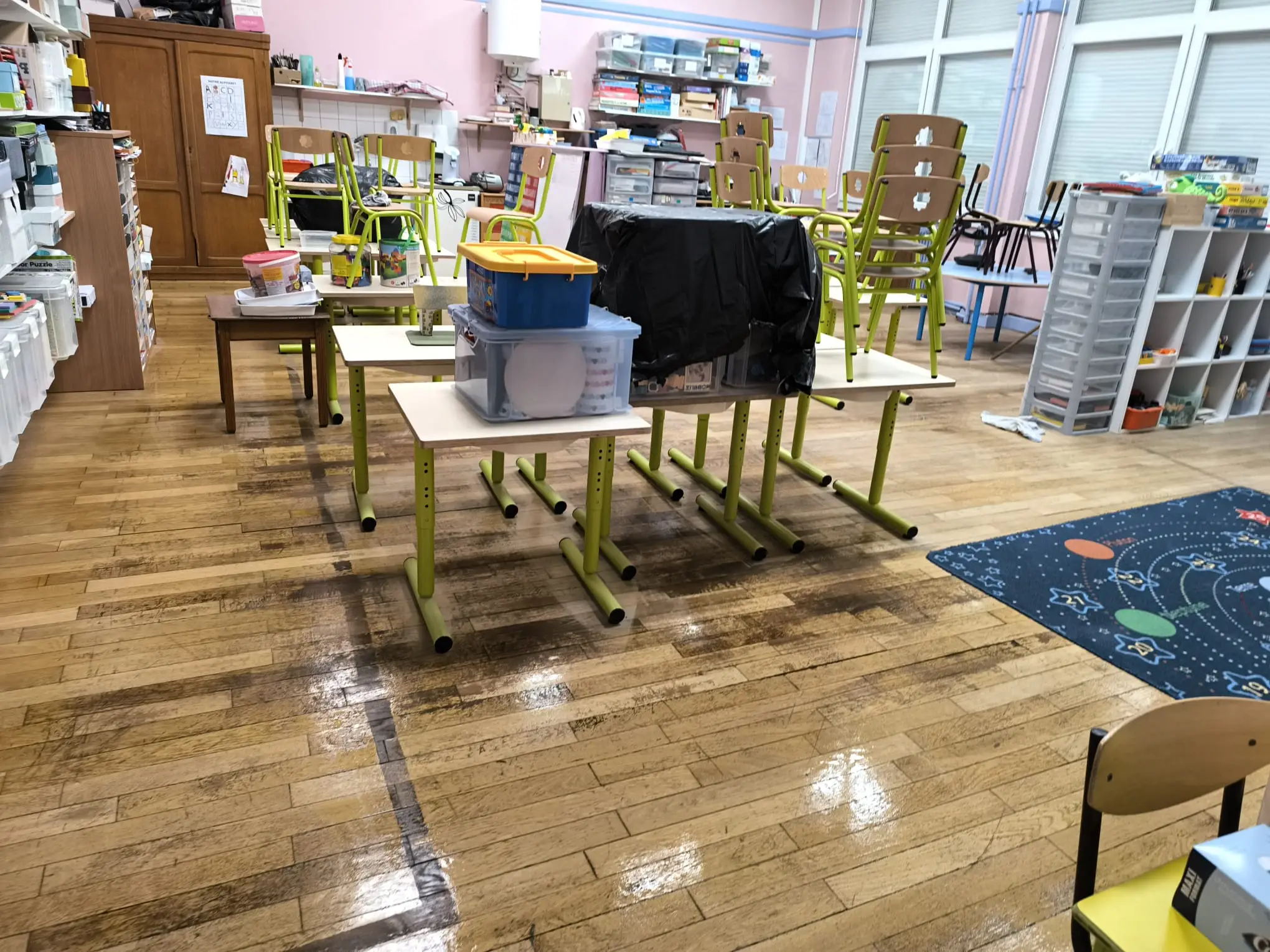 Salle de classe d’école maternelle avec parquet décapé et lustré, chaises et tables empilées
