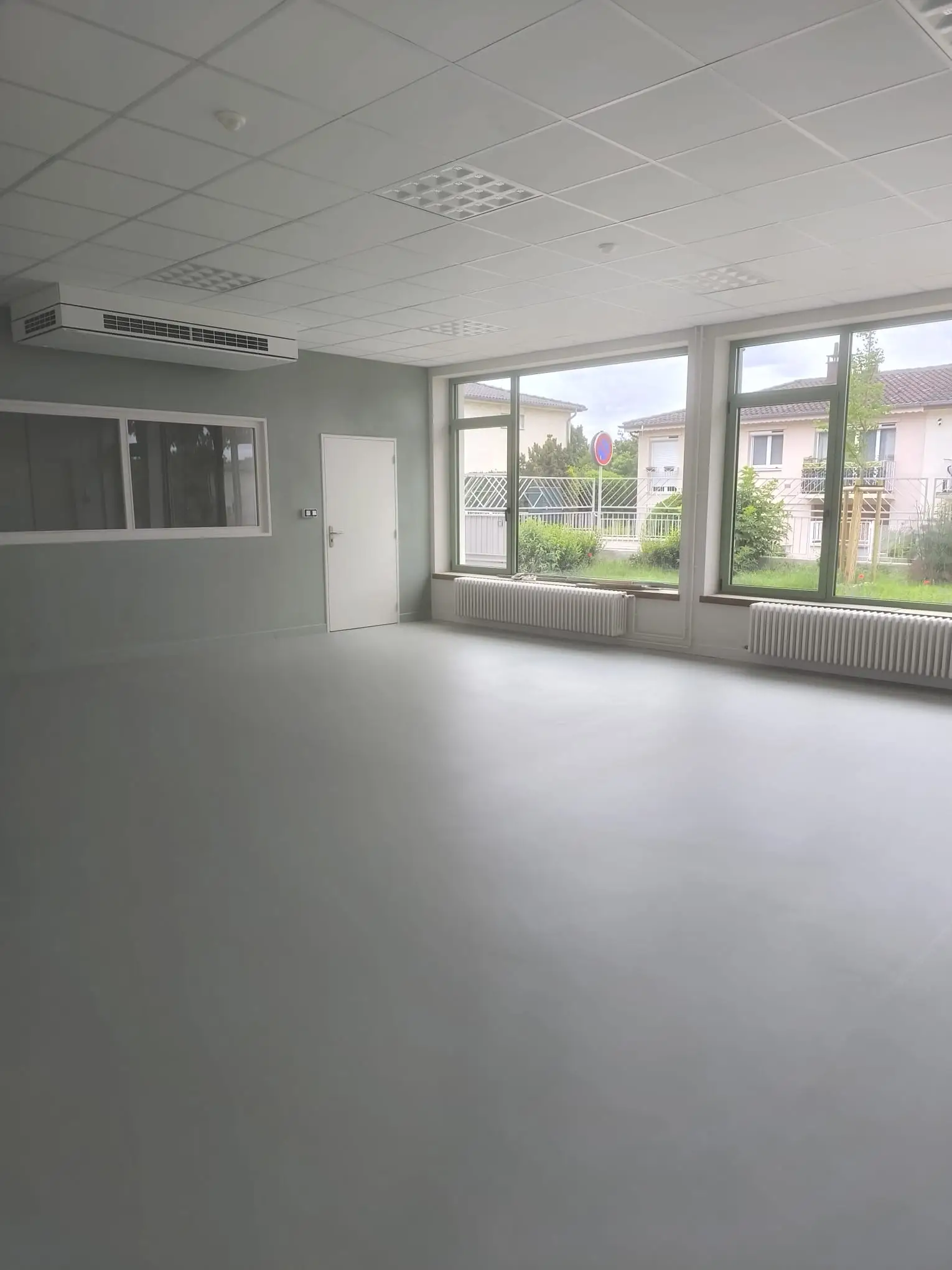 Local professionnel après travaux avec sol en résine nettoyé et grandes baies vitrées dégagées