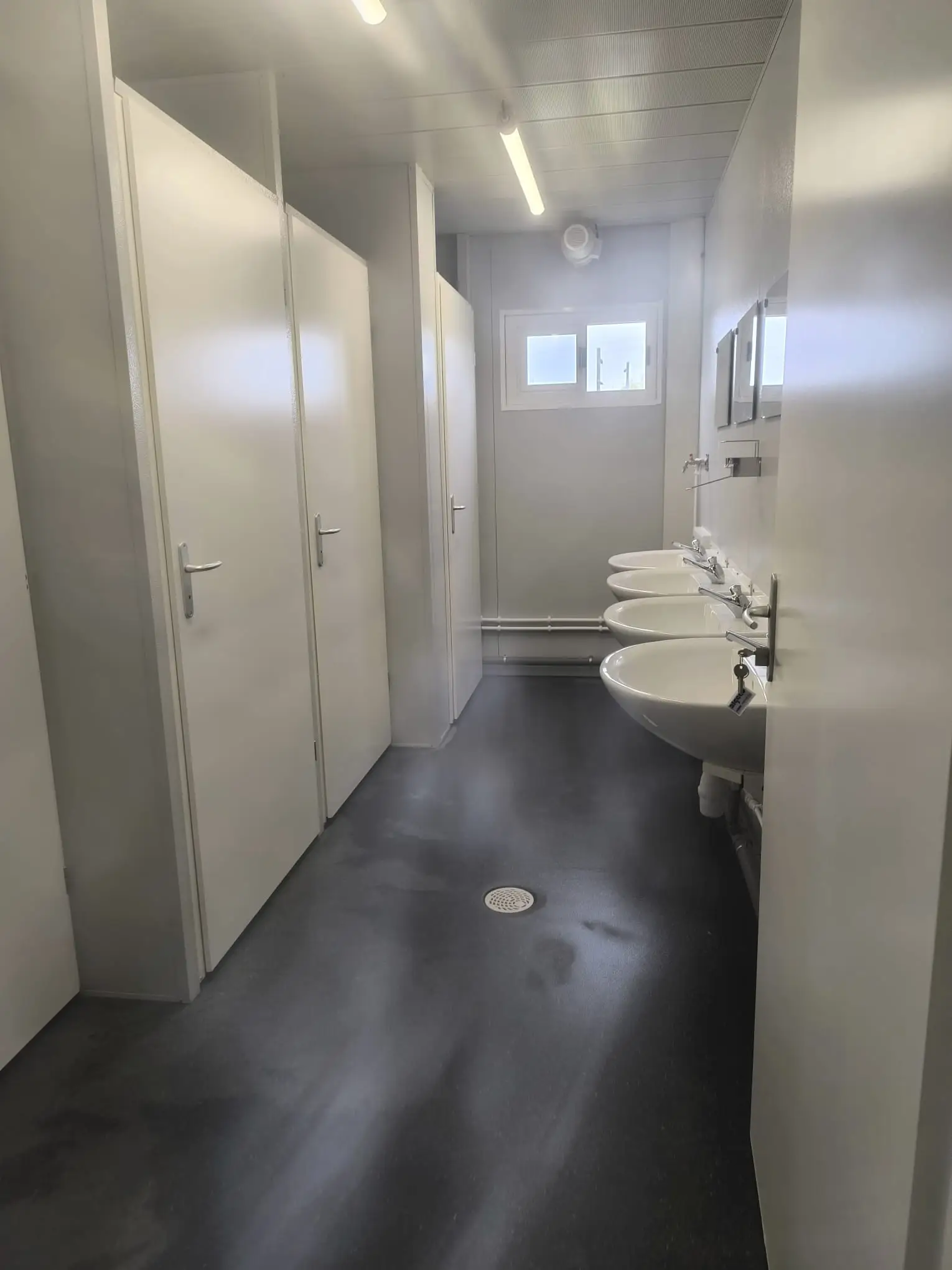 Bloc sanitaire collectif neuf, lavabos et cabines nettoyés après fin de chantier
